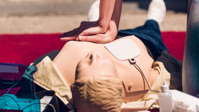 Borstcompressies op een reanimatiepop met AED-elektrode